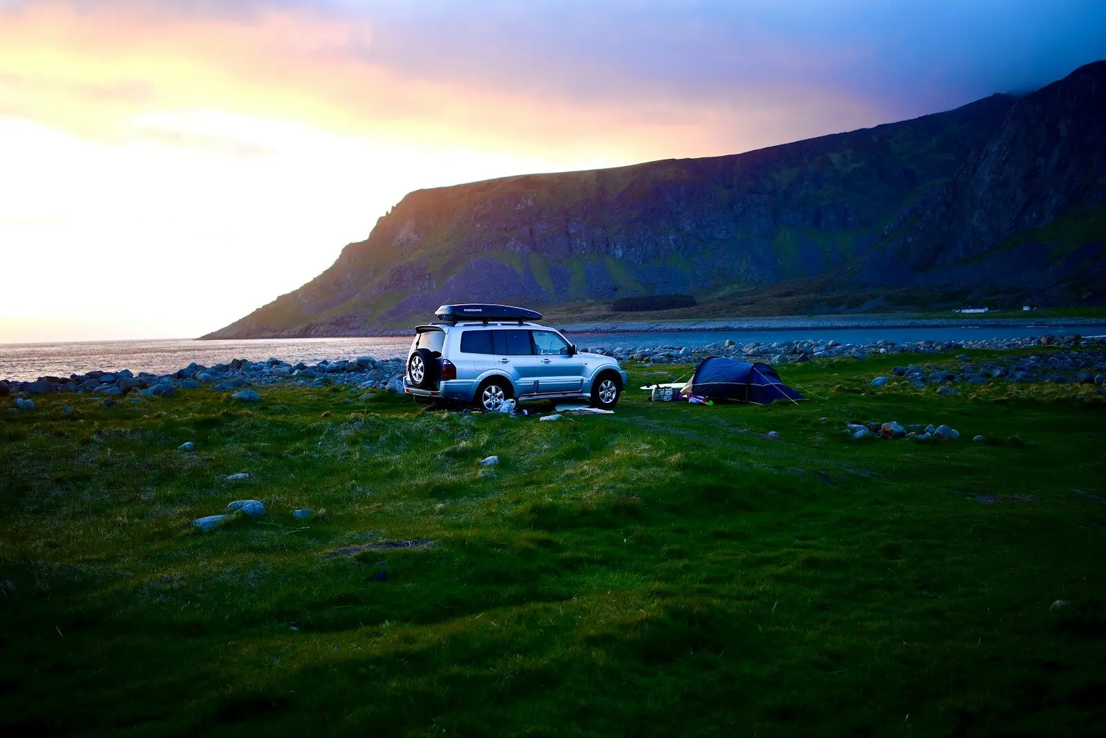 a car parked in a field next to a tent