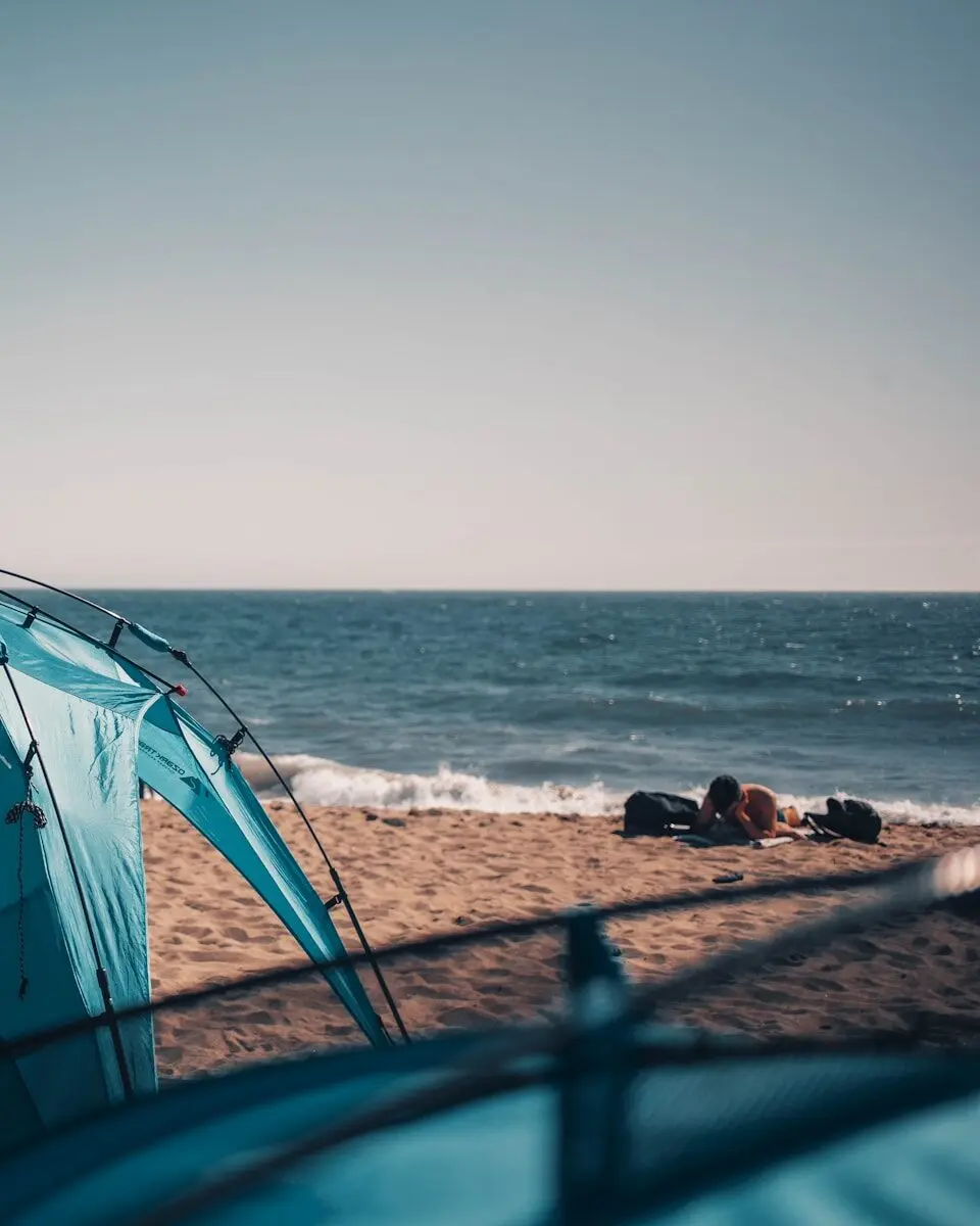 a blue tent sitting on top of a sandy beach