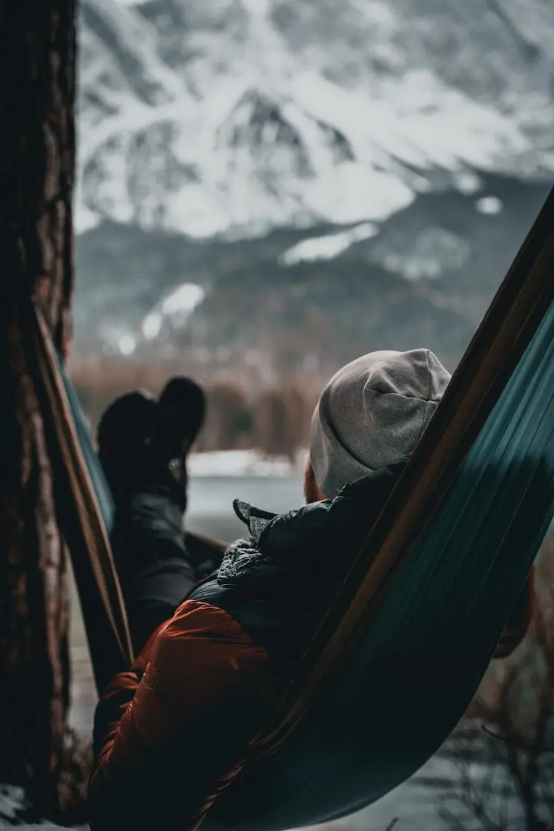 a person laying in a hammock next to a tree